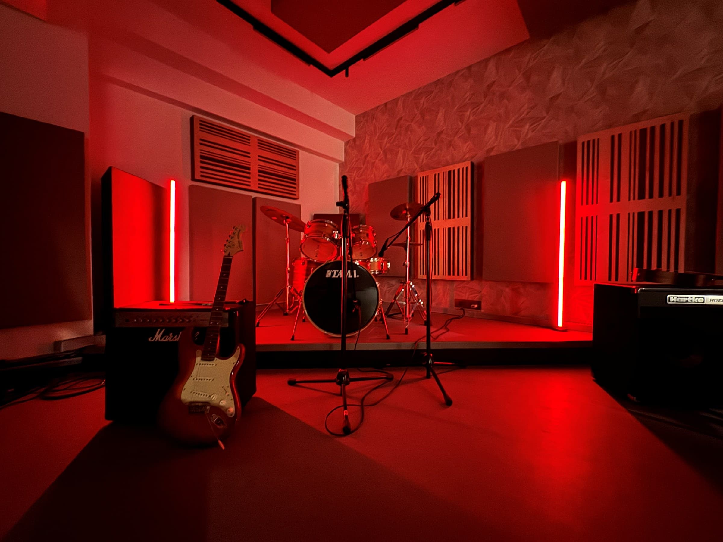 Kings Club Studio live room with red lighting, drum kit and guitar